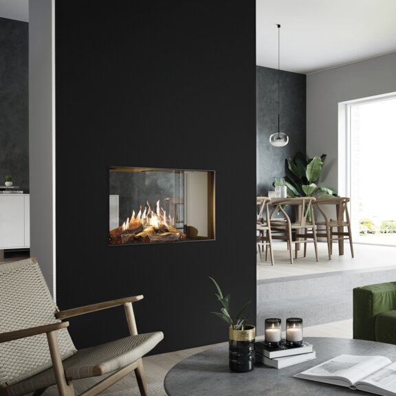 Gas-Kamin VISIO 70 T steht als Tunnel in einer schwarzen Trennwand und strukturiert so den Wohnraum zwischen Küche, Esszimmer und Wohnzimmer