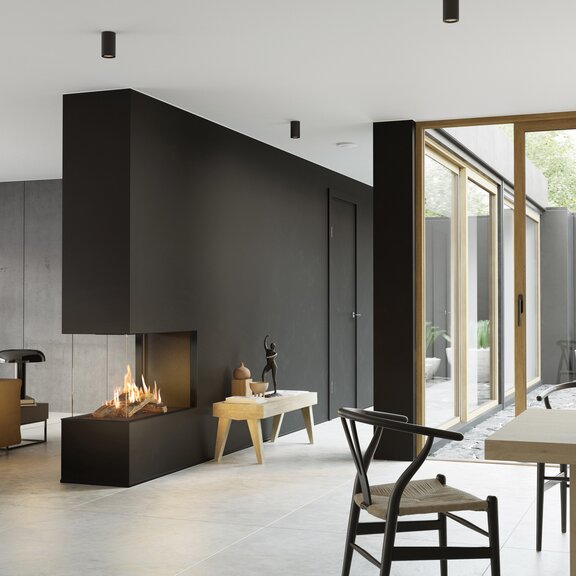 Il camino a gas VISIO 90 RD si adatta perfettamente come divisorio per ambienti in una parete nera tra il soggiorno e la sala da pranzo e dà struttura al soggiorno arredato in modo semplice