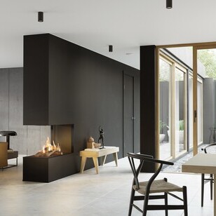 Il camino a gas VISIO 90 RD si adatta perfettamente come divisorio per ambienti in una parete nera tra il soggiorno e la sala da pranzo e dà struttura al soggiorno arredato in modo semplice