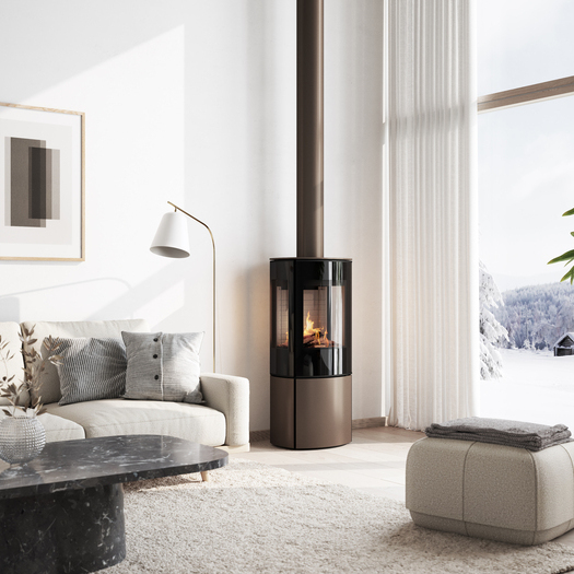 Stufa a gas CARO 110 in versione moca con porta del focolare a vetro pieno e finestra laterale nell'accogliente soggiorno