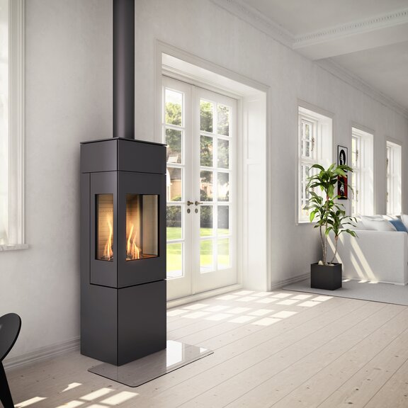 Stufa a gas NEXO 140 in nero con porta in acciaio e due finestre laterali in un soggiorno luminoso