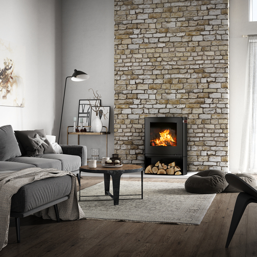 Stufa a legna Q-TEE 2 C in nero con scomparto per la legna nella sua forma leggermente ovale come caminetto in una casa di campagna rustica