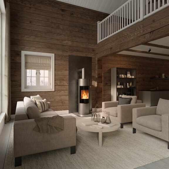 Stufa a legna VIVA 140 L in colore platino con porta del focolare in vetro pieno su una parete in legno in una casa rustica